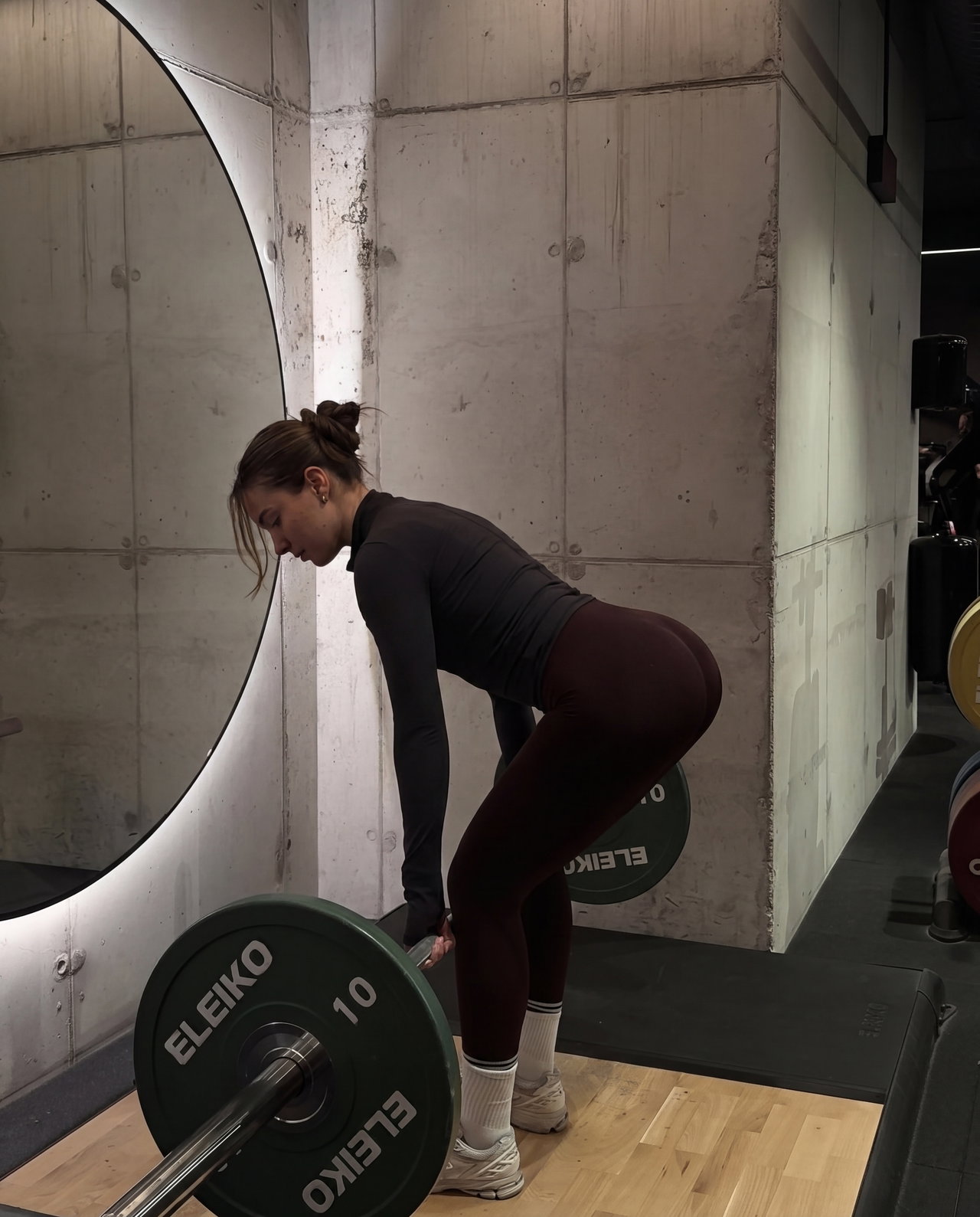 Person Preparing to Lift Barbell in Modern Gym