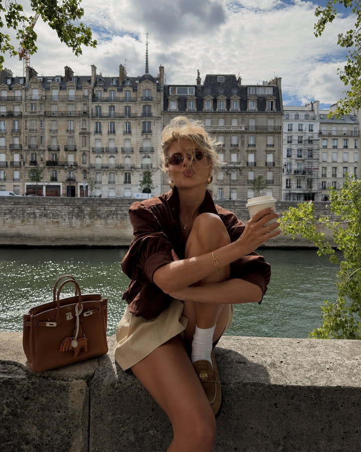 Young Woman Relaxing by River with Parisian Architecture