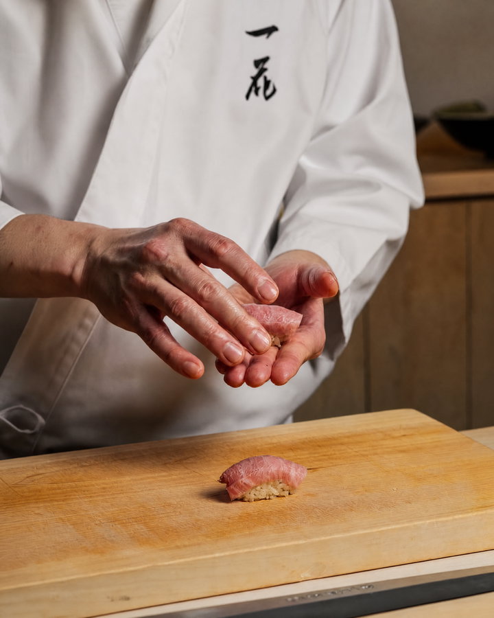 Sushi Chef Shaping Sushi on Wooden Cutting Board