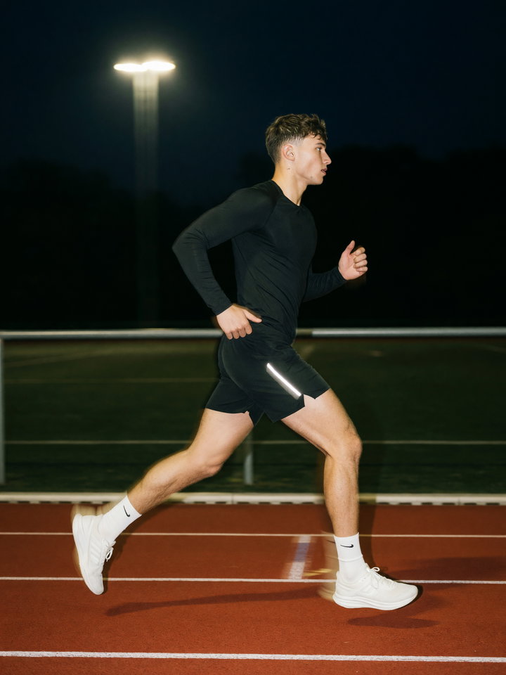 Athletic Runner on Red Track at Night
