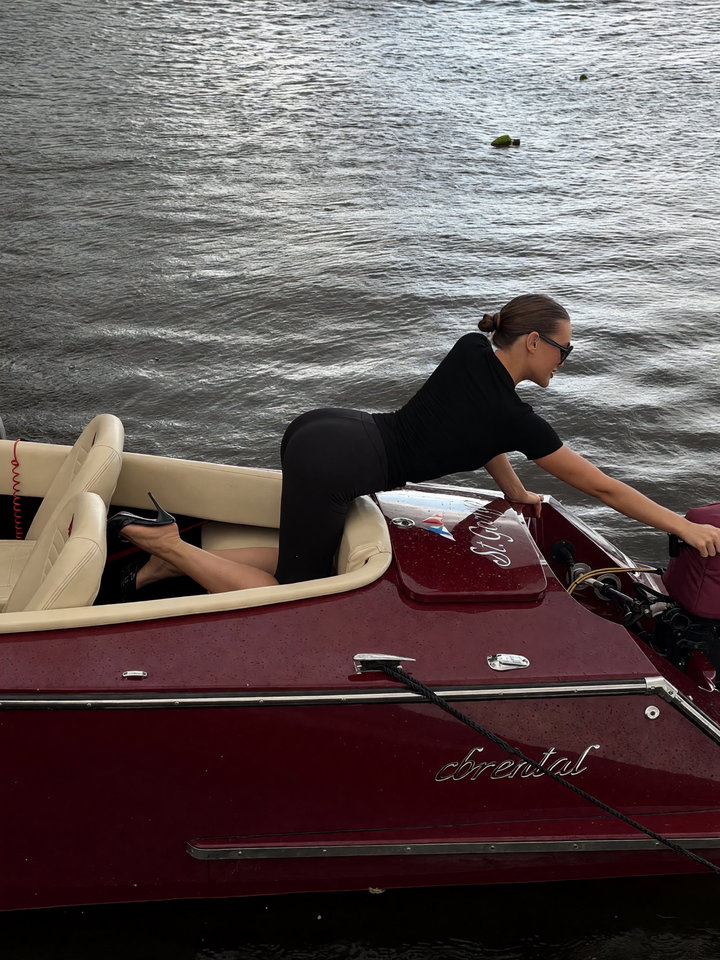 Person in Black Outfit on Luxurious Maroon Boat