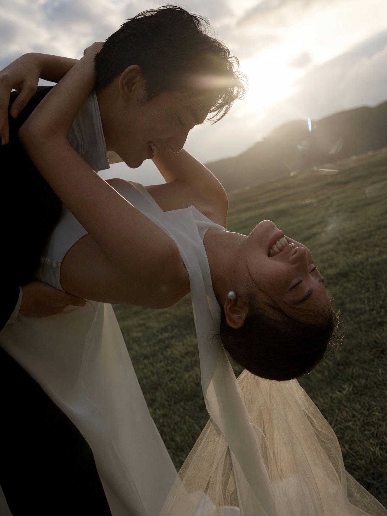 Joyful Couple Embracing in Grassy Field at Sunset
