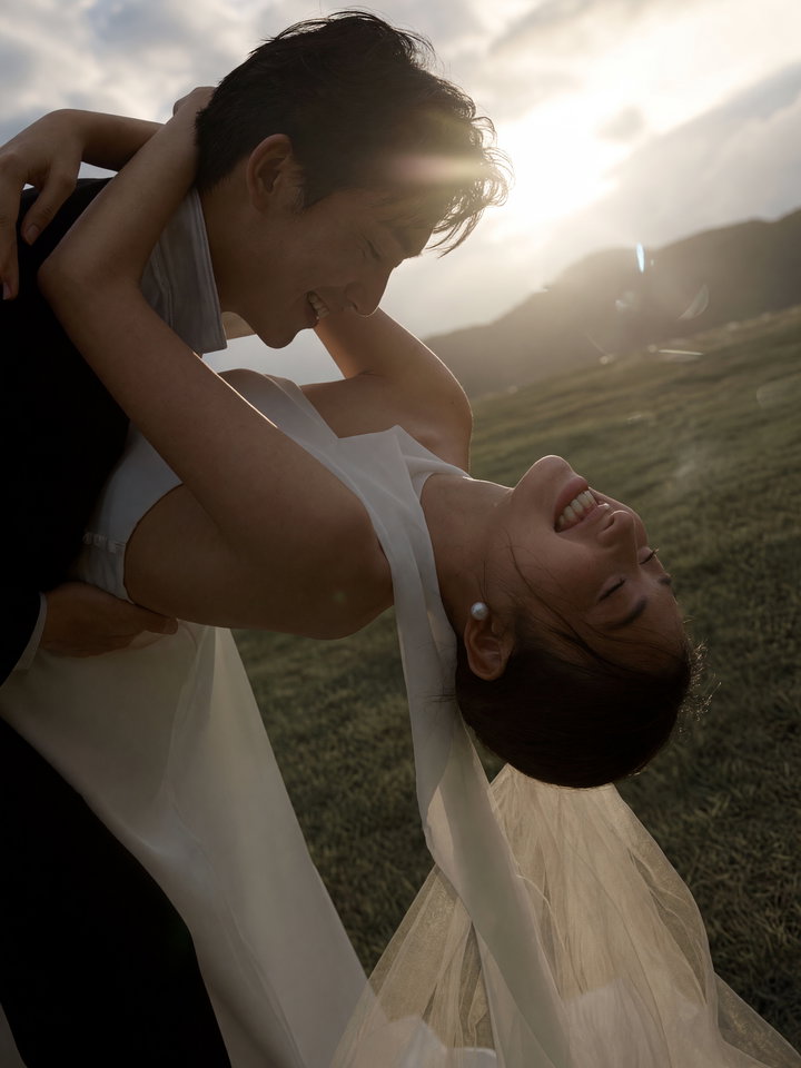 Joyful Couple Embracing in Grassy Field at Sunset