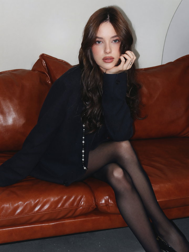 Young Woman in Black Blazer on Leather Couch