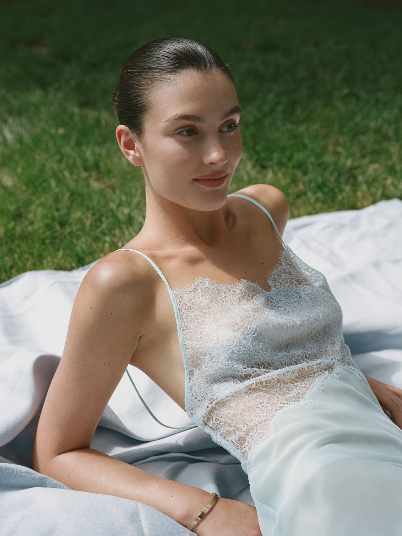 Young Woman Reclining on Light Blue Blanket in Grass