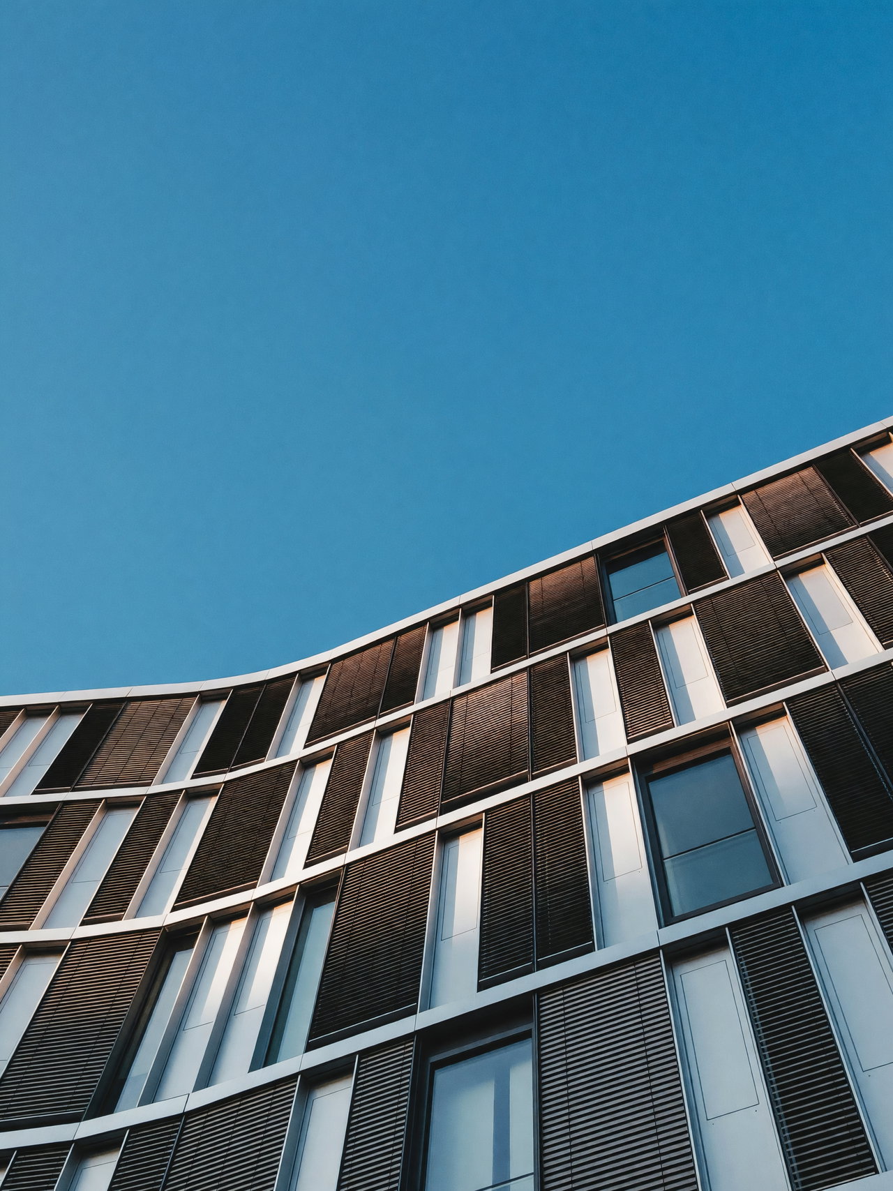 Curved Modern Building Facade Against Clear Blue Sky