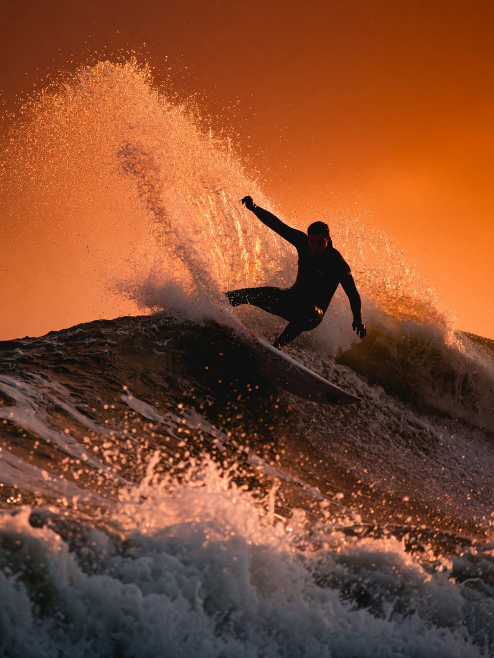 Surfer Riding Wave at Sunset