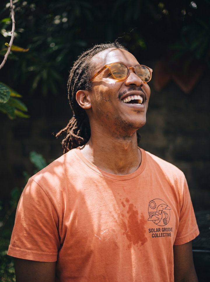 Laughing Man with Short Locs and Amber Glasses
