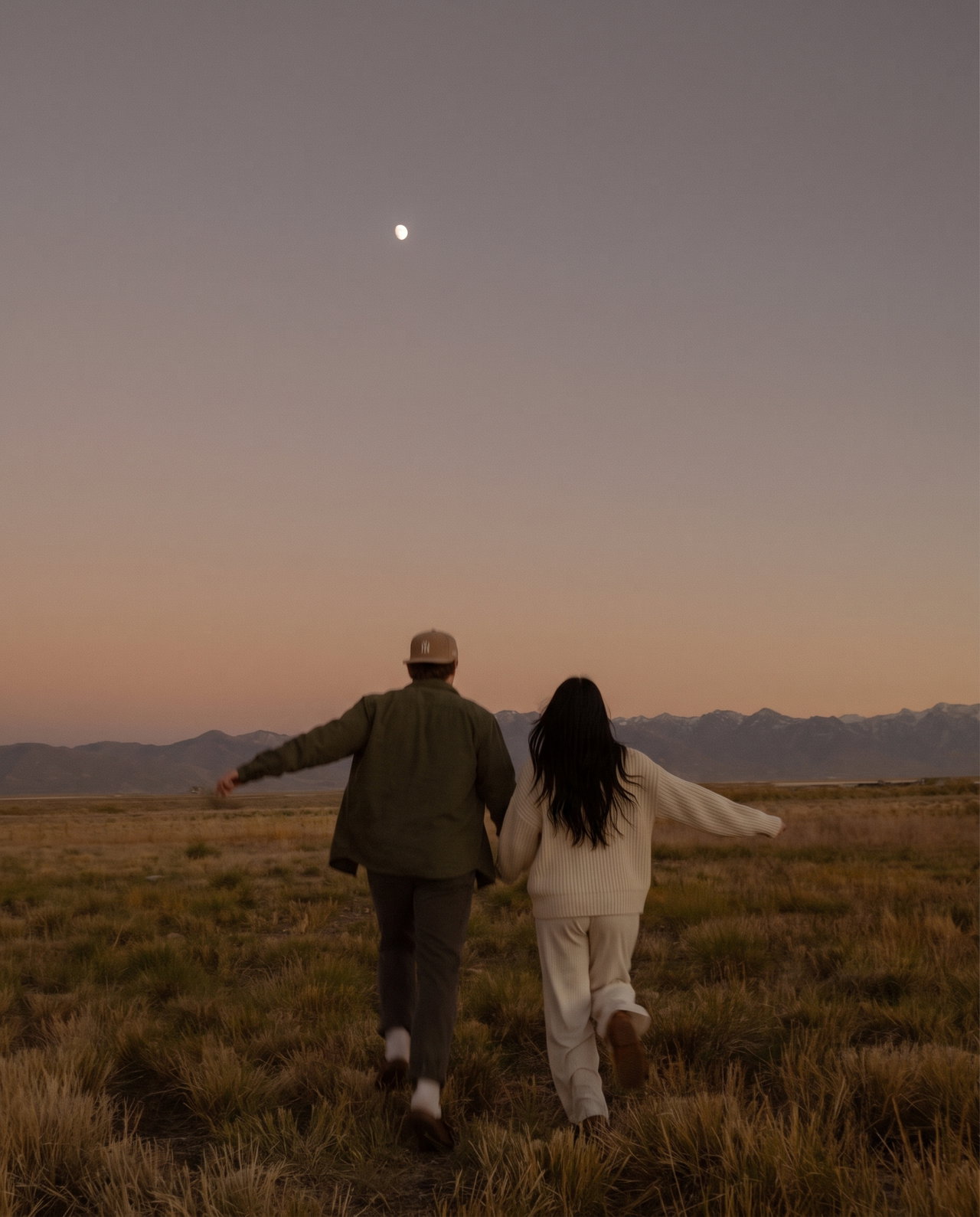 Couple Running Through Field at Dusk