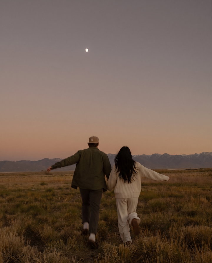 Couple Running Through Field at Dusk