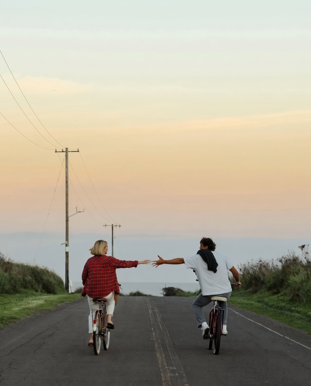 Friends Cycling on Coastal Road at Sunset