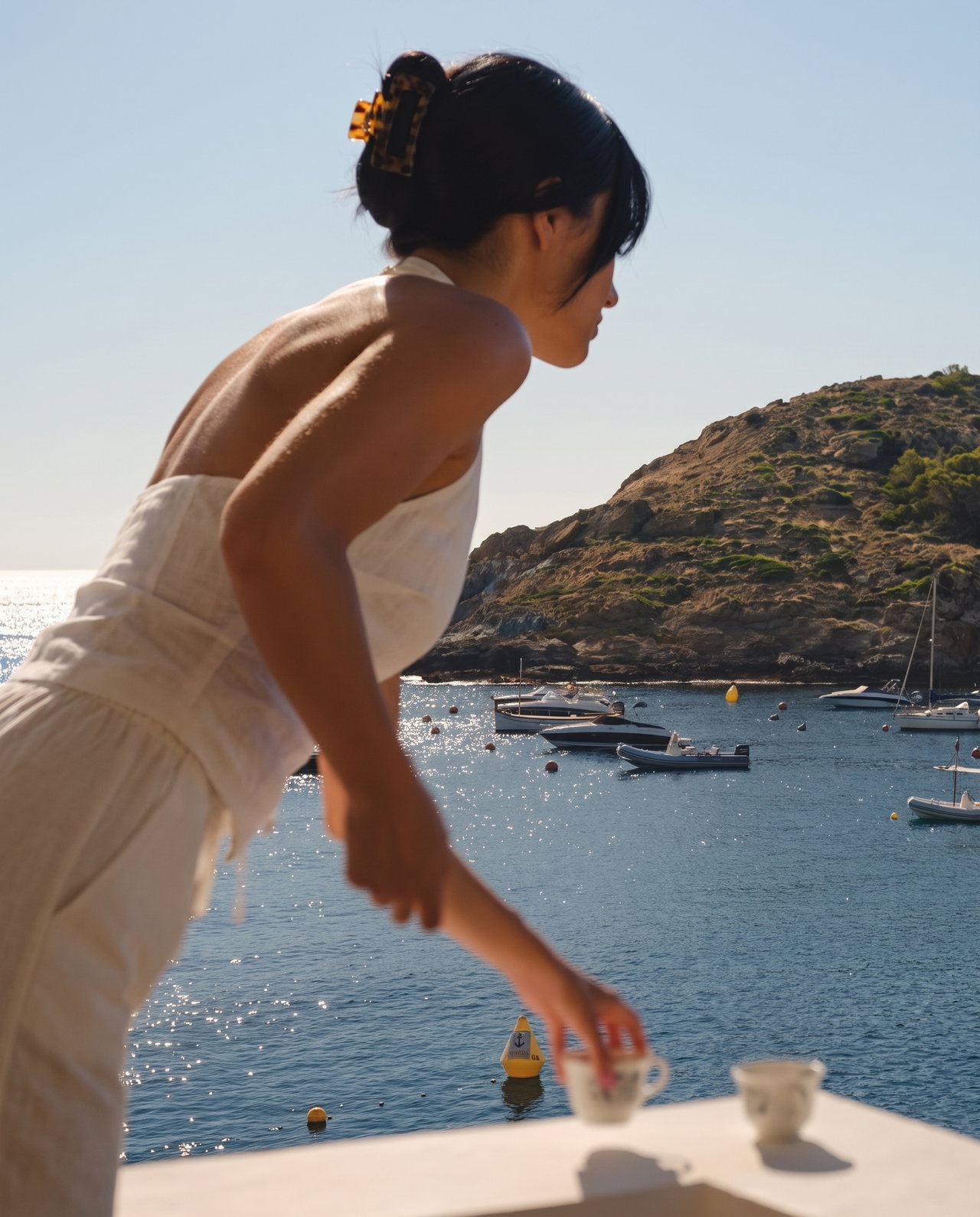 Woman Setting Down Coffee on Mediterranean Terrace