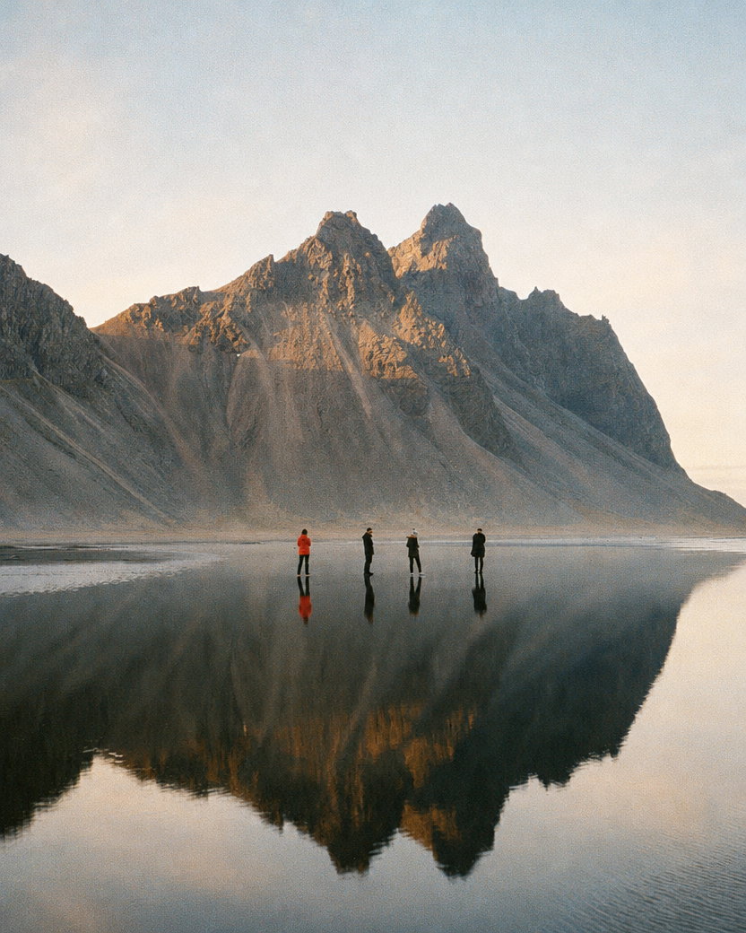 Hikers by Mountain Reflection in Black-Sand Lagoon