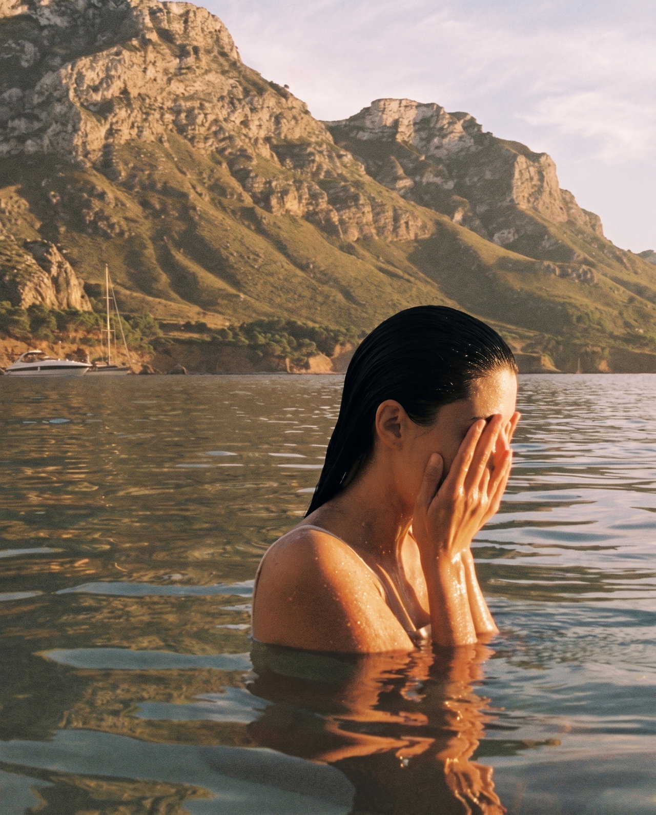 Woman Covering Face in Calm Bay at Golden Hour