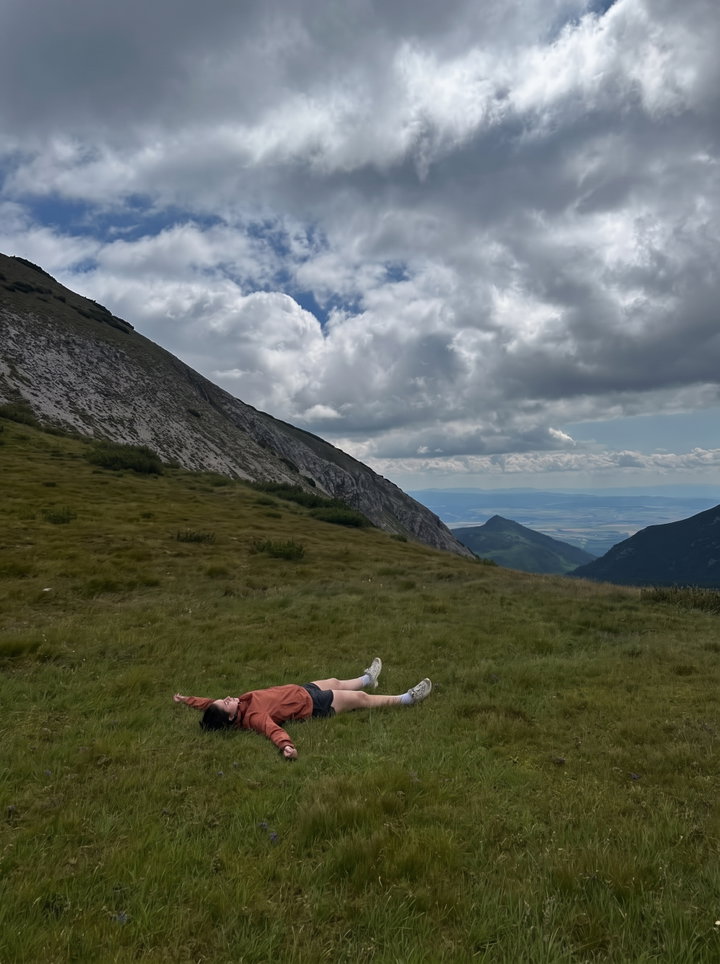 Person Lying in Grass on Mountain Hillside