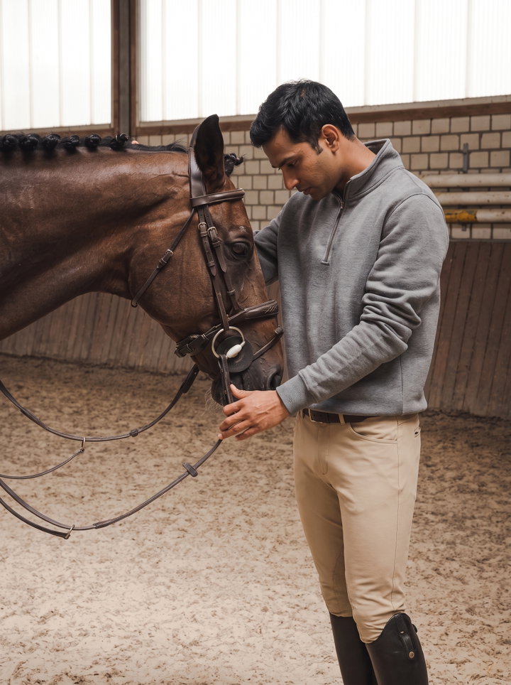 Man Adjusting Bridle on Horse in Indoor Arena