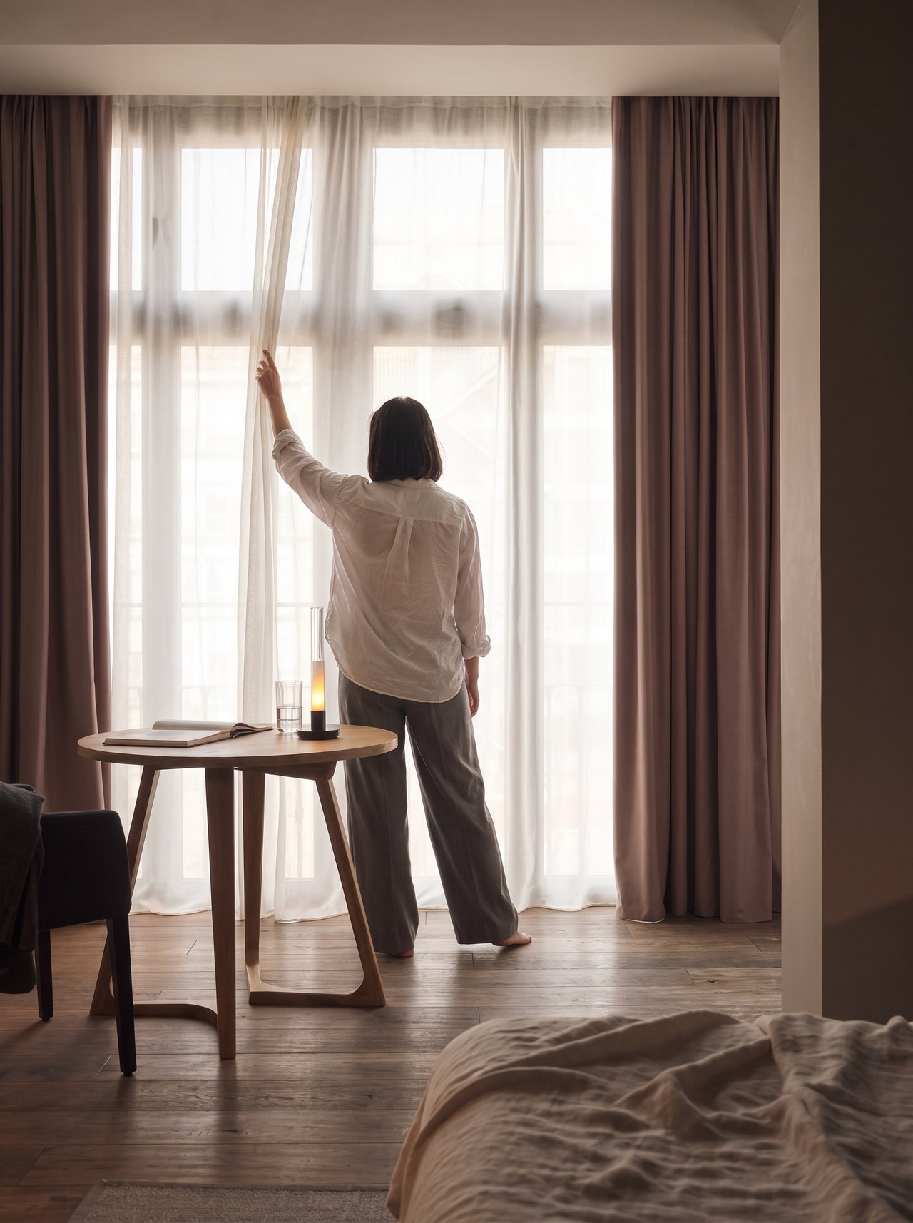Woman Opening Curtains in Hotel Room